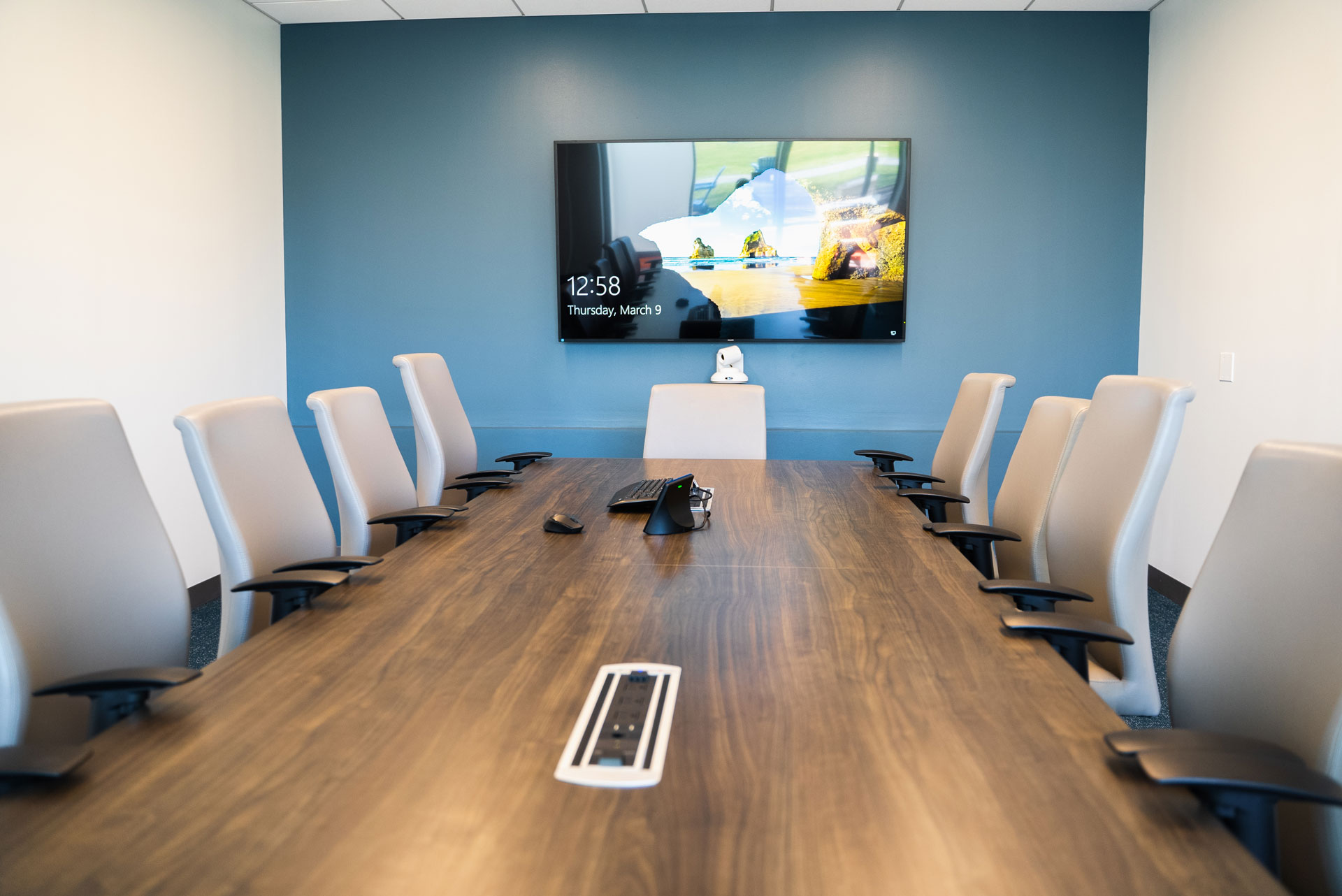 Conference room table with a monitor mounted to the wall at the other end