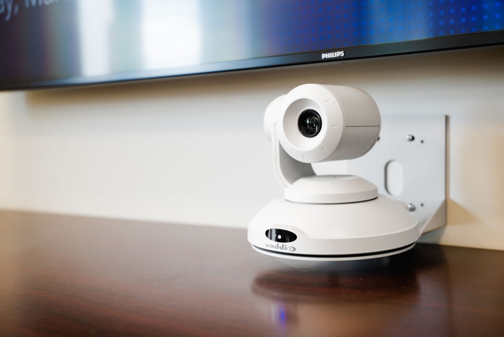 Closeup of a video conferencing camera mounted to the wall