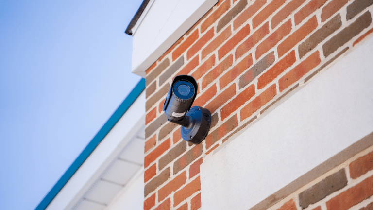 A black security camera secured to a brick wall