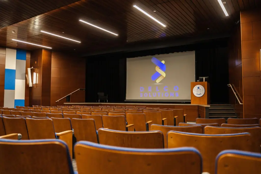 Auditorium AV setup with a projector going to a screen and a podium to speak at